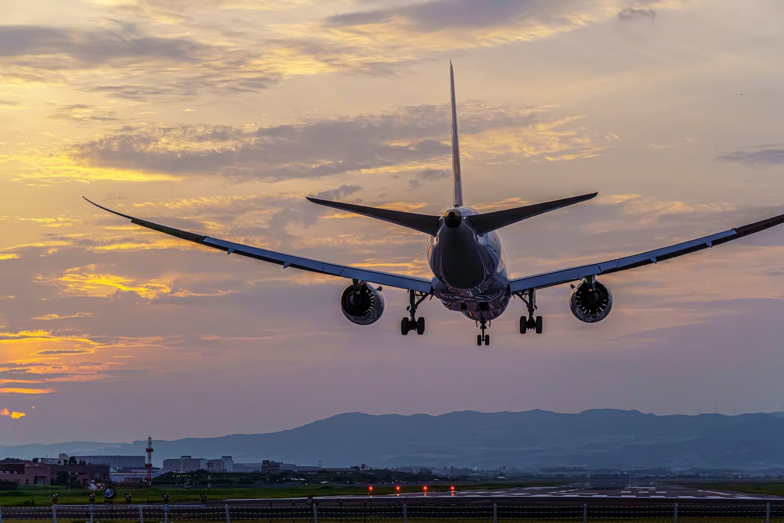 Airplane approaching for landing over a mountain range at sunset